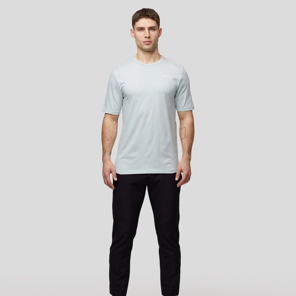 Man wearing a light blue McLaren F1 Lando Norris Core Essentials T-shirt and black trousers.