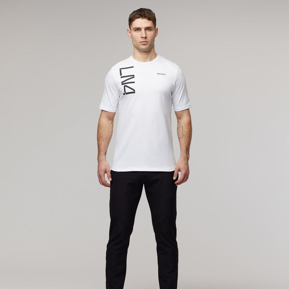 Man wearing a white Lando Norris McLaren F1 Core T-shirt and black pants.